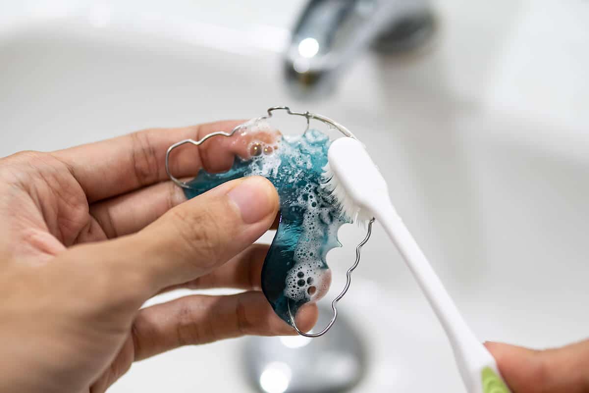 cleaning a retainer with a toothbrush after learning how to clean a retainer