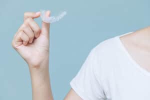 Aperson holding up a and Invisalign clear aligner