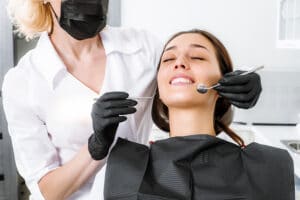A young woman laying back in a dental treatment chair while the dental hygienist begin her work